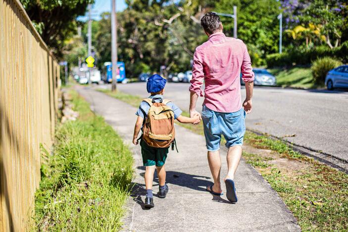 School child and father walking on a path